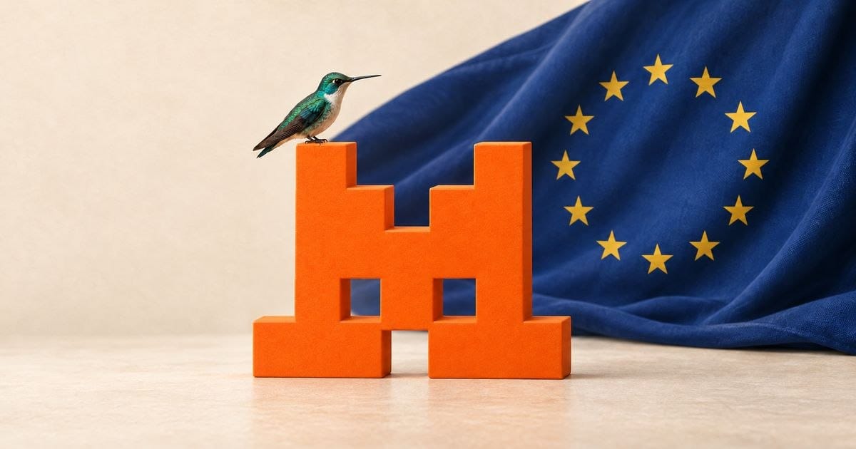 Ein Kolibri sitzt auf einem orangefarbenen Mistral-M vor einer Europaflagge.